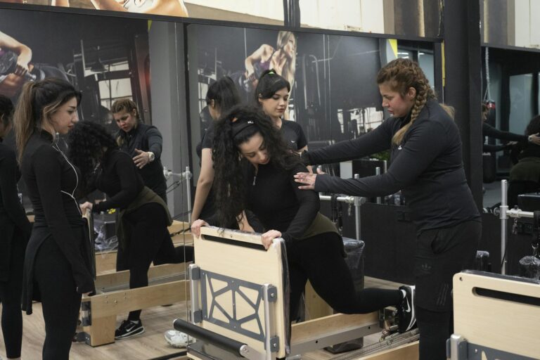 A dynamic group pilates session with focused instructor assistance in a modern gym.