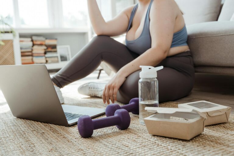 Plus size woman exercising at home with purple dumbbells, showcasing healthy lifestyle.