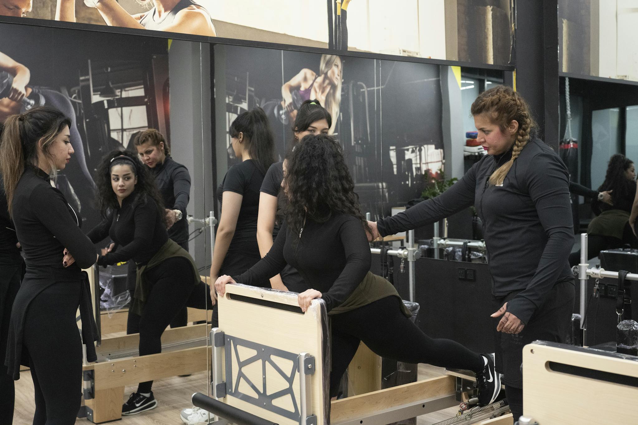 Women engaging in a Pilates class with reformer equipment in a modern studio setting.